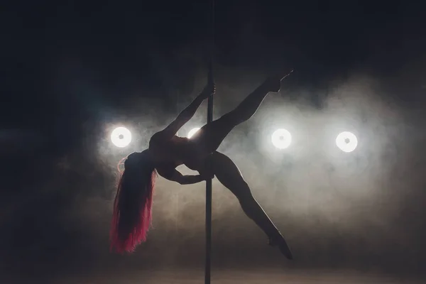 Giovane donna sottile pole dance in interni scuri con luci e fumo . — Foto Stock