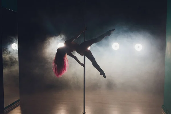 Giovane donna sottile pole dance in interni scuri con luci e fumo . — Foto Stock