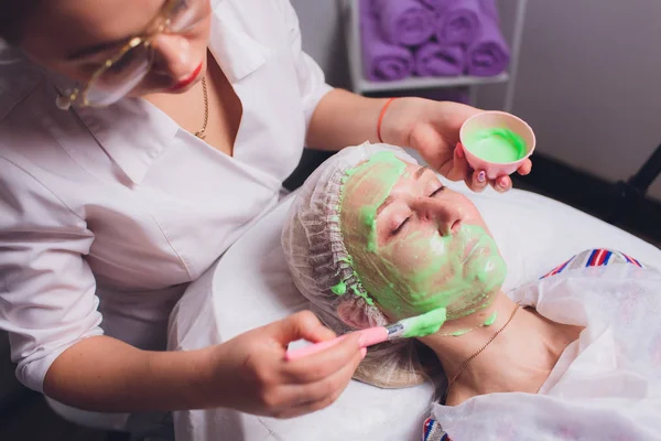 Yeşil algler genç bir kadının yaşlanmaya karşı tedavi spa maskeden özel makyaj fırça yardımıyla güzellik uzmanı yapar. — Stok fotoğraf