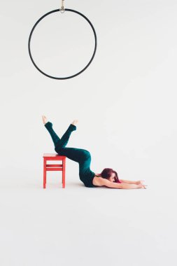Genç kadın bir sandalyede akrobasi yapıyor. Beyaz backgound, izole.