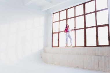 güzel kadın büyük pencere yakın yoga ve akrobasi yapıyor.