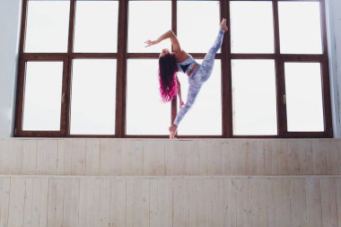 güzel kadın büyük pencere yakın yoga ve akrobasi yapıyor.