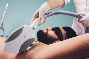 Lazer koltuk altı epilasyon tedavisi sırasında güzellik yatarken erkekler.