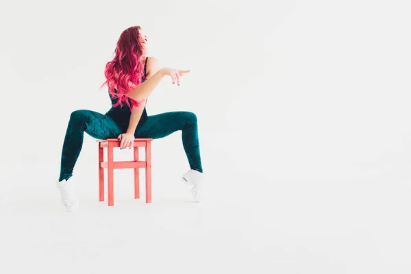Ung kvinna gör akrobatik på en stol. Vit backgound, isolerad. — Stockfoto