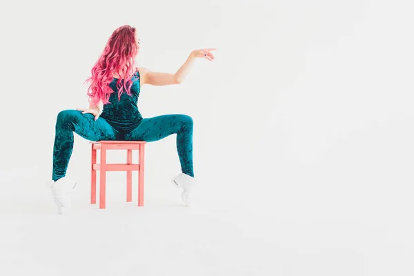 Young woman doing acrobatics on a chair. White backgound, isolated. — Stock Photo, Image