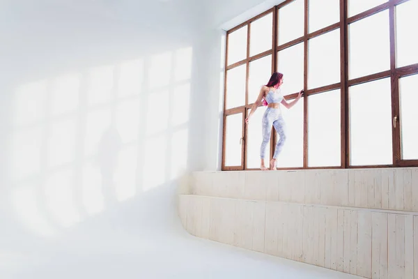 Bela mulher fazendo ioga e acrobacias perto da grande janela . — Fotografia de Stock