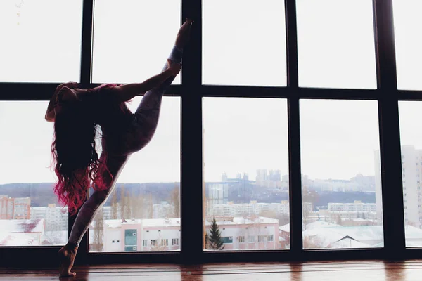 Bella donna che fa yoga e acrobazie vicino alla grande finestra . — Foto Stock