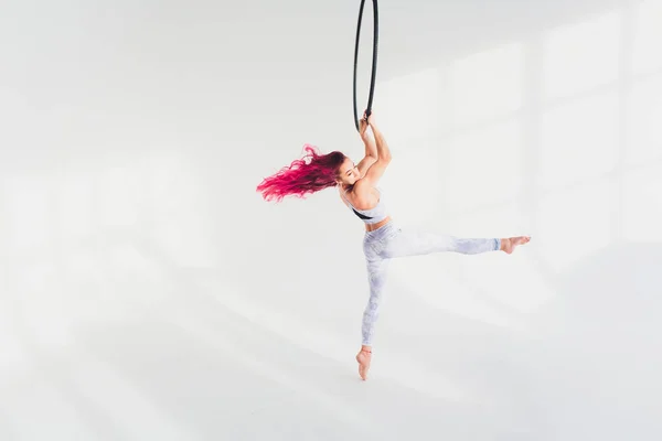 Young redhead woman performs acrobatic elements in the air ring on a white background. — Stock Photo, Image