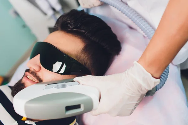 Hombre joven recibiendo tratamiento de depilación láser en el centro de belleza . —  Fotos de Stock