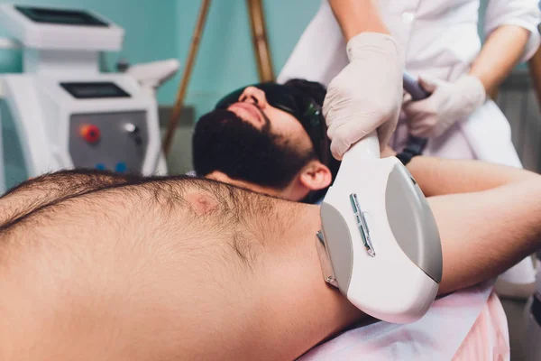 Hombres acostados en esteticistas durante la terapia de depilación por axila láser . —  Fotos de Stock