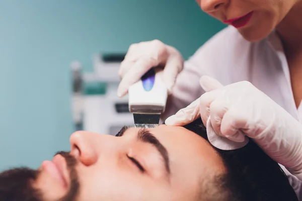 Ultrasonic face cleaning. Young caucasian man, cosmetology.