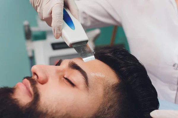 Limpieza ultrasónica del rostro. Hombre joven caucásico, cosmetología . —  Fotos de Stock