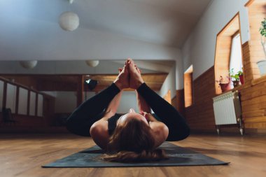 Sportif kadın pratik yoga, ardha Padmasana egzersiz, yarım Lotus poz mudra hareketi ile çalışma dışarı yaparak spor giyim gri pantolon ve üst, cesedi yakın, yoga stüdyosu giyiyor. Dikkatli hayat kavramı