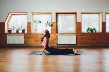 Cobra egzersiz, Bhujangasana poz, çalışma dışarı uzanan pratik yoga kavramı, genç yogi çekici kadın giyim spor giyim, siyah kolsuz bluz ve pantolon, tam uzunlukta, beyaz loft arka plan.