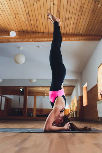 Yoga kavramı pratik genç Yogi çekici kadın, sancak karasan egzersiz ayakta, amuda kalkma poz, çalışma dışarı, spor giyim, siyah tank üst ve pantolon, tam uzunlukta, çatı arka plan giymek.