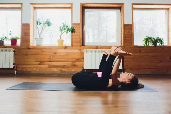 젊은 매력적인 여자 연습 요가, Ananda Balasana 운동, 운동, 행복 한 아기 포즈에에서 스트레칭 보기 측면 회색 스튜디오 배경, 전체 길이, 멋진 도시 스타일, 블랙 운동복을 입고 — 스톡 사진