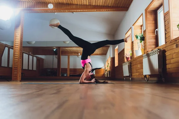 Junge Yogi attraktive Frau praktiziert Yoga-Konzept, steht in Salamba Sirsasana-Übung, Kopfstand-Pose, trainiert, trägt Sportbekleidung, schwarzes Tank-Top und Hose, volle Länge, Loft-Hintergrund. Stockbild