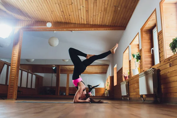 Junge Yogi attraktive Frau praktiziert Yoga-Konzept, steht in Salamba Sirsasana-Übung, Kopfstand-Pose, trainiert, trägt Sportbekleidung, schwarzes Tank-Top und Hose, volle Länge, Loft-Hintergrund. lizenzfreie Stockbilder
