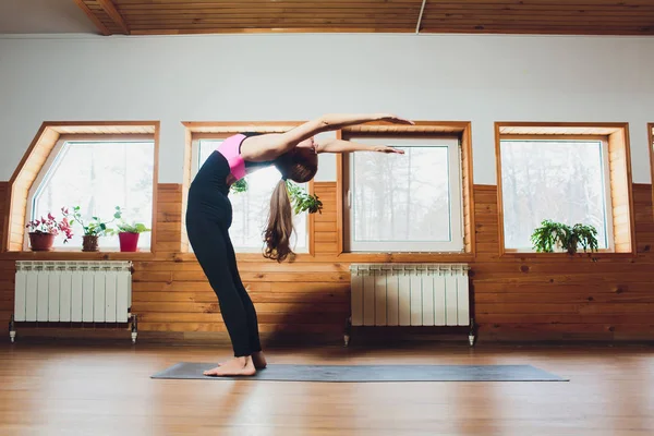 Junge sportliche Frau praktiziert Yoga, macht Surya-Yantrasana-Übungen, Kompass-Pose, trainiert, trägt Sportbekleidung, Hose und Top, drinnen in voller Länge, weißes Yoga-Studio. Stockfoto