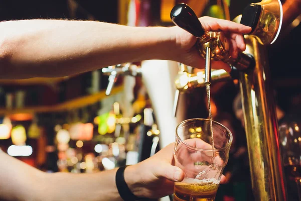 We ontmoeten oktoberfest. Hand van barman gieten een grote pils in kraan. Gieten van bier voor client. Zijkant van jonge barman gieten bier terwijl staande aan de bar teller. — Stockfoto