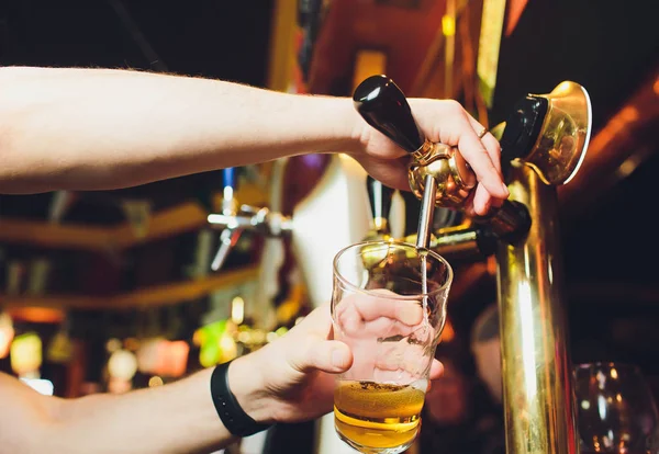 Nos encontramos con el Oktoberfest. Mano de cantinero vertiendo una gran cerveza de cerveza en el grifo. Verter cerveza para el cliente. Vista lateral del camarero joven vertiendo cerveza mientras está de pie en el mostrador del bar . — Foto de Stock