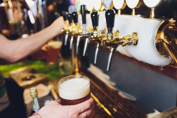 Nous rencontrons Oktoberfest. Main de barman versant une grande bière blonde dans le robinet. Verser de la bière pour le client. Vue latérale du jeune barman versant de la bière debout au comptoir du bar . — Photo
