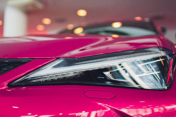 Close up shot headlight in luxury pink car background. Modern and expensive sport car concept.