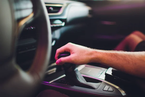 Empresario que conduce un coche moderno de lujo en la ciudad. Cerrar mans mano en la caja de cambios . — Foto de Stock