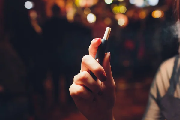 Tecnologia dei prodotti del tabacco non bruciati termicamente. Donna che tiene la sigaretta elettronica in mano prima di fumare. — Foto Stock