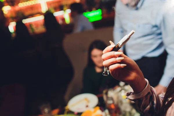 Tecnología de productos de tabaco sin combustión por calor. Mujer sosteniendo el cigarrillo electrónico en su mano antes de fumar. — Foto de Stock