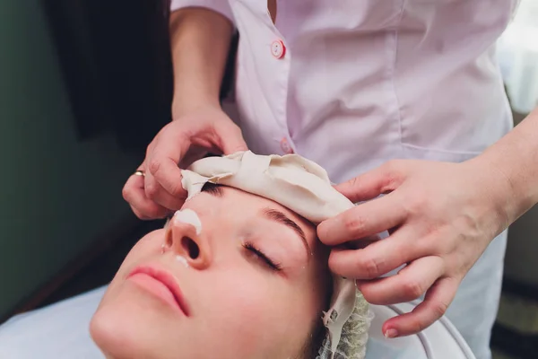 Процедури обличчя. Гарний кваліфікований косметолог знімає маску під час процедури краси . — стокове фото