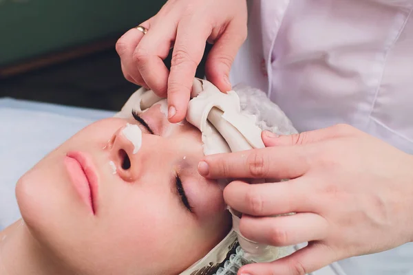 Процедури обличчя. Гарний кваліфікований косметолог знімає маску під час процедури краси . — стокове фото