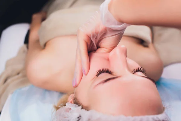 Kozmetolog hastaların yüz kasları bir bukkal masaj yapar.