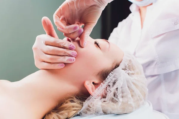 Kosmetolog vyrábí bukové masáže pacientů na obličejové svaly. — Stock fotografie