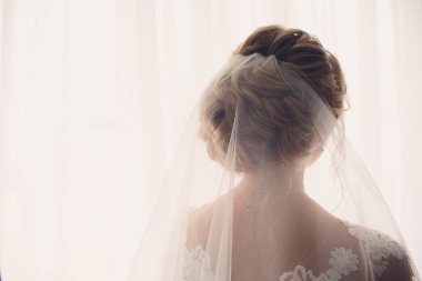 Gelin, pencerede elbise giymişti. Güneşli bir gün. gün ışığı.