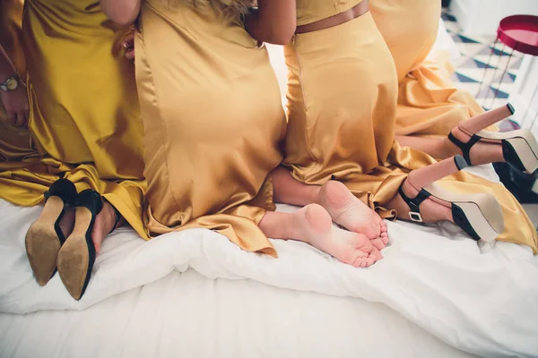 Imagen de chicas caucásicas con estilo de 20 años usando vestidos probándose diferentes zapatos de verano o tacones altos durante la despedida de soltera en el acogedor dormitorio . —  Fotos de Stock