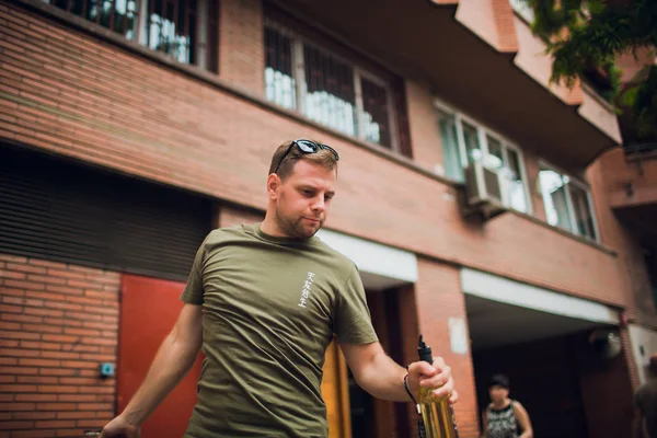 De jonge man opent een wijn fles in de straat. — Stockfoto