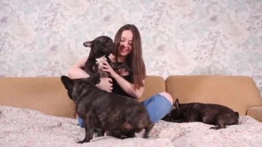 Güzel bir genç kız oturur ve bir Fransız bulldog köpek küçük köpek yavrusu bir sürü tutar.