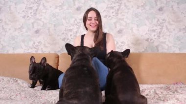 Güzel bir genç kız oturur ve bir Fransız bulldog köpek küçük köpek yavrusu bir sürü tutar.