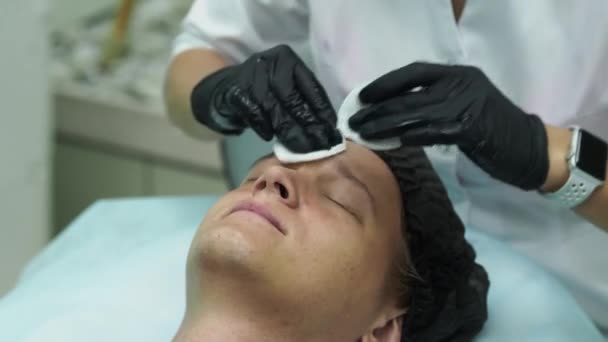 Cosmetologia masculina. Jovem do sexo masculino recebendo procedimentos faciais na clínica de beleza. Pele descascada . — Vídeo de Stock