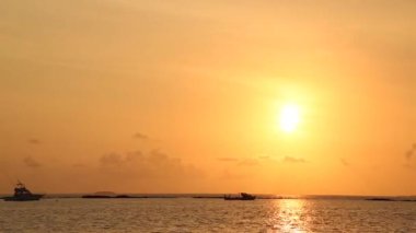 Turuncu gökyüzü, kara bulutlar ve ufukta ada ile Maldivler adada renkli gün batımı Pürüzsüz timelapse. Güneş ufukta batıyor. İnsanların yokluğu.