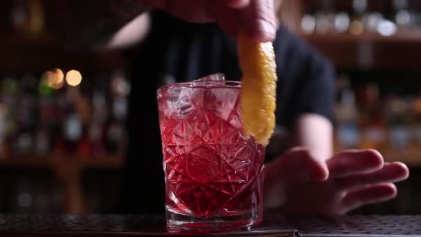 Barman s händer bevattning saften i cocktailglas fyllt med alkoholhaltiga drycker på den mörka bakgrunden. — Stockvideo