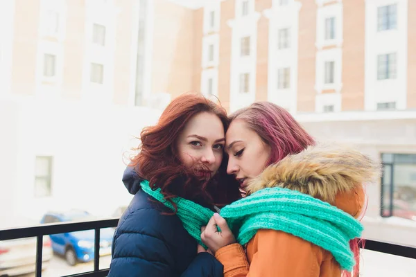 Lesbiana Pareja de mujeres jóvenes. Chica lleva sombrero caliente chica cierra los oídos amigos con las manos en manoplas en invierno frío . —  Fotos de Stock