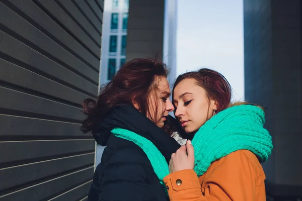 Leszbikus pár fiatal nő. Lány visel meleg kalap lány bezárja barátai füle a kezével ujjatlan hideg télen. — Stock Fotó