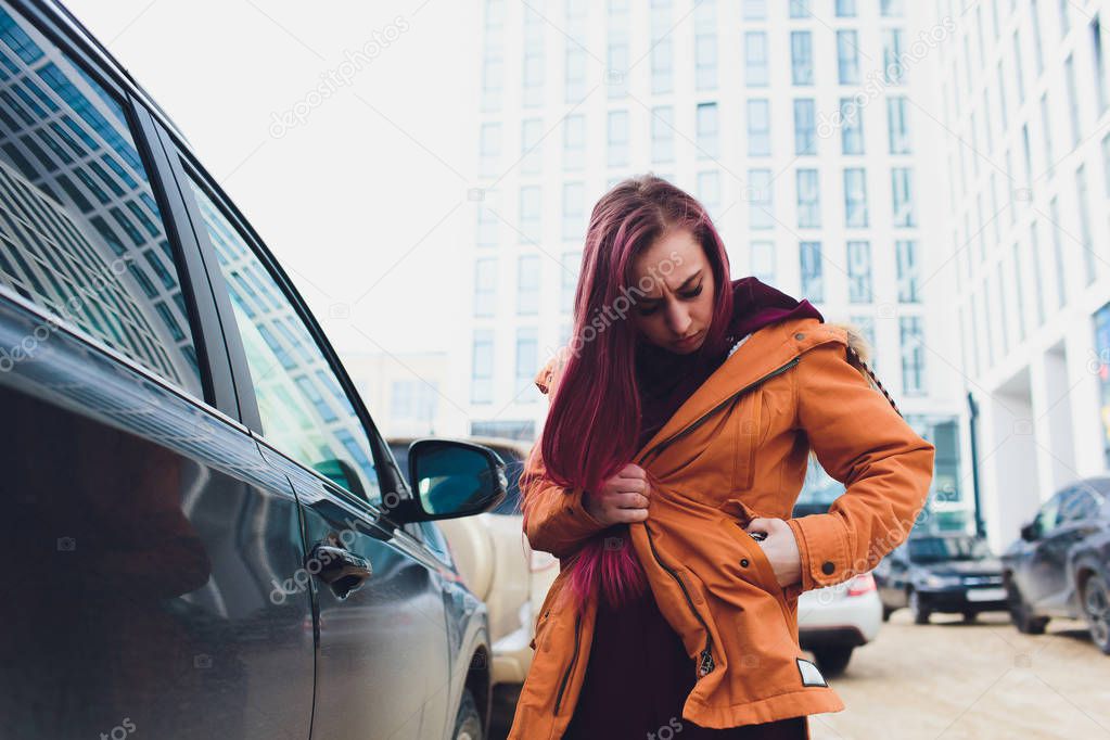 Pretty young woman standing and looking keys of car in her bag outdoors.
