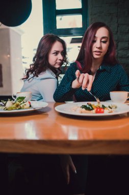 İki mutsuz lezbiyen kahve dükkanında öğle yemeği sırasında kavga ettikten sonra birbirleriyle konuşmuyor: üzgün kızıl saçlı kadın yalnız hissederken kız arkadaşı yanında otururken.