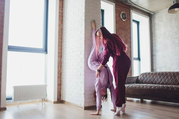 Professionnel deux athlètes féminines sont assises en position de yoga ensemble. Ils se touchent les bras et se regardent avec sérénité. Soleil de la grande fenêtre . — Photo