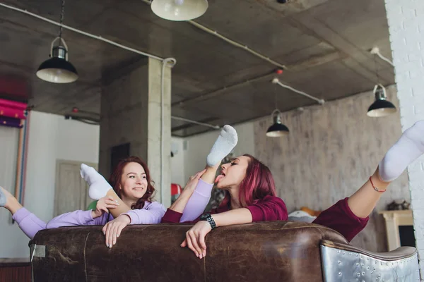 LMBT aranyos fiatal lányok mosolyogva, flörtölni a kanapén otthon. — Stock Fotó
