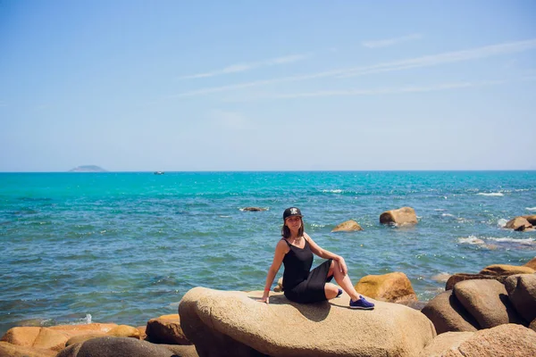 Жінка мандрівник сидить і дивиться на край скелі на березі моря Азія . — стокове фото