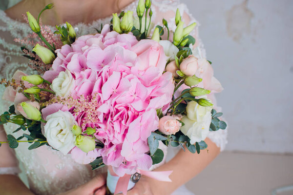 the bride is holding a bouquet of the bride from white roses and eustoma.
